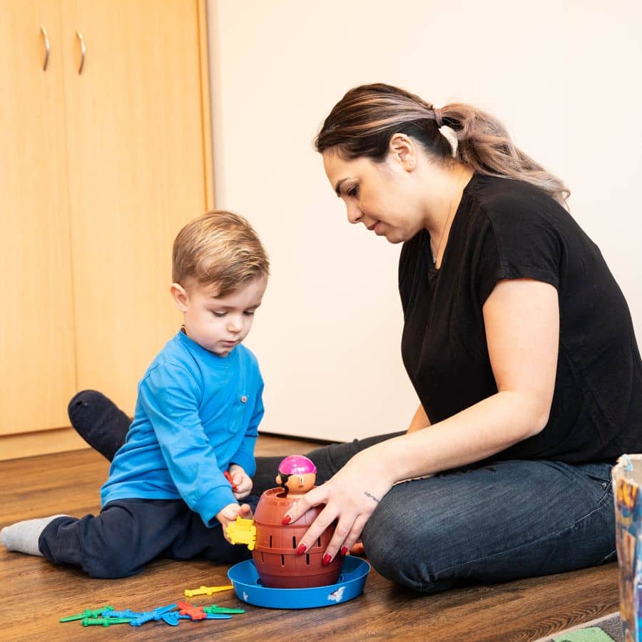 Kind spielt mit Spielzeug und Betreuerin begleitet ihn