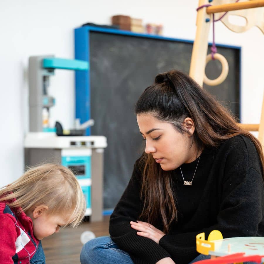 Betreuerin spielt mit Kindern an einer Spielmatte